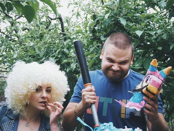 Portrait of woman in wig with man against tree