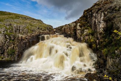 Scenic view of waterfall against sky