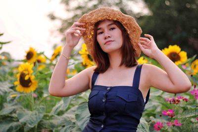 Portrait of beautiful young woman standing by flowering plants