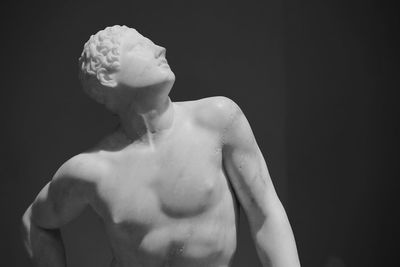 Portrait of shirtless man standing against black background