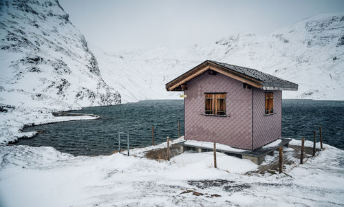 Hut by snowcapped mountain against sky