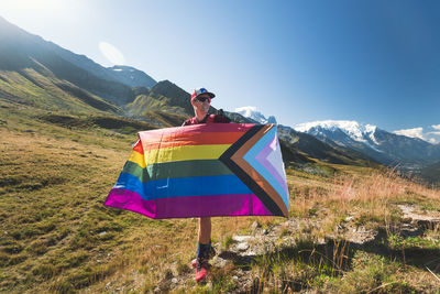 Man holding lgbtiq community flag in mountains