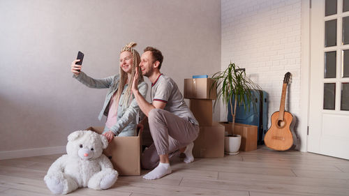 Woman video conferencing over phone with man while moving house on floor