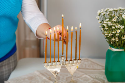 Midsection of woman holding candle on table