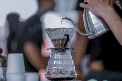 Close-up of hand pouring coffee in cafe