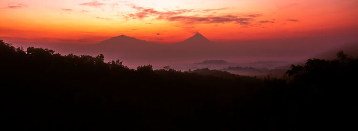 Scenic view of silhouette mountains against orange sky