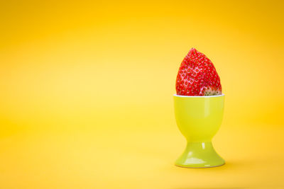 Strawberry in eggcup against yellow background