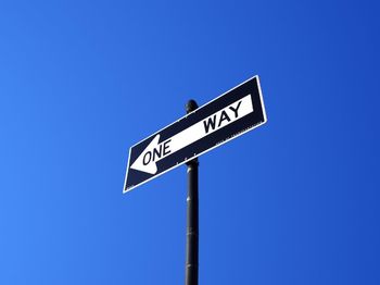 Low angle view of sign board against blue sky