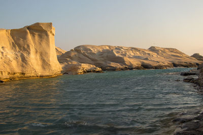 Rock formations by sea against clear sky