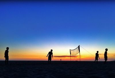 Silhouette of woman standing on beach at sunset