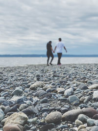 People on rocks at beach against sky