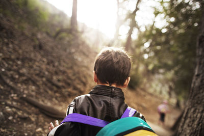 Rear view of boy walking in forest