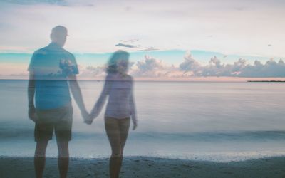 Double exposure of couple holding hands at beach