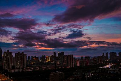 Cityscape against cloudy sky during sunset