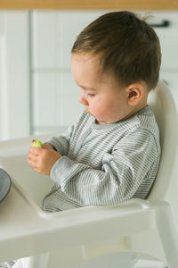 Portrait of cute baby boy eating food at home