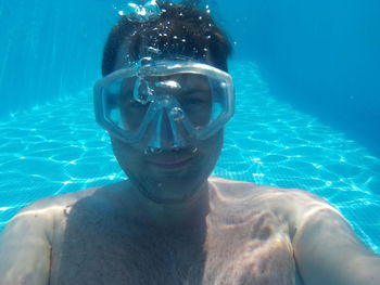 Portrait of shirtless man wearing scuba mask under swimming pool