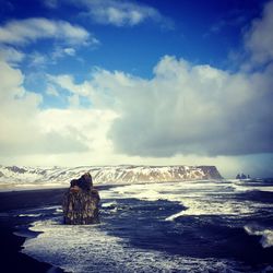 Snow covered landscape against cloudy sky