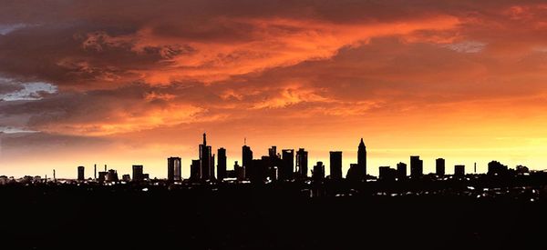 Silhouette of buildings against cloudy sky during sunset