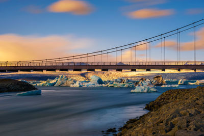 Bridge over river against cloudy sky