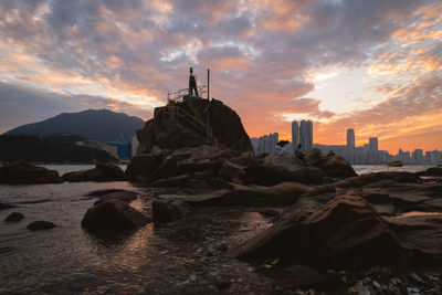 Rock formations by sea against sky during sunset