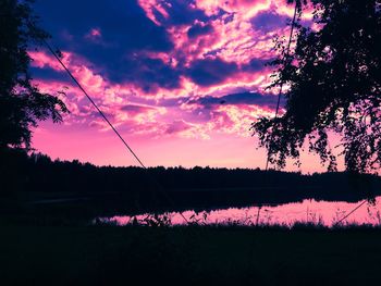 Silhouette trees by lake against sky during sunset
