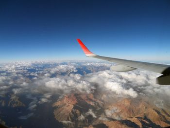 Airplane flying over clouds against blue sky