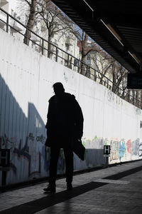 Rear view of silhouette man walking on footpath in city