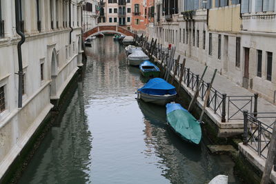 Boats moored in canal amidst buildings in city