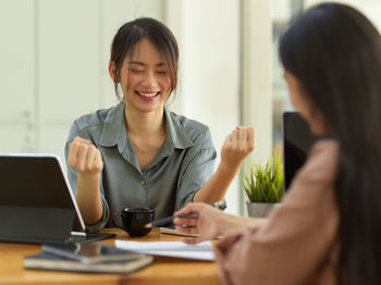 Businesswoman holding fist while sitting at office