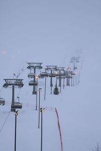 Electricity pylon by sea against clear sky during winter