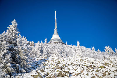 Low angle view of snow covered temple against blue sky