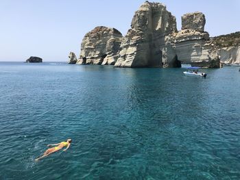 Boat in sea against rock formation