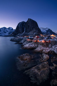 Scenic view of illuminated houses by lake against clear sky