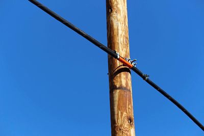 Low angle view of wood against clear blue sky