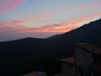 Houses by mountains against sky at sunset