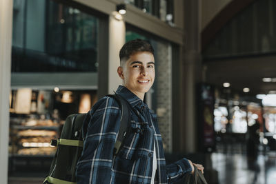 Side view of smiling boy wearing plaid shirt at station