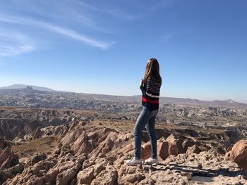 Woman standing on rock against sky