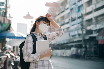 Woman wearing protective mask while standing on street in city