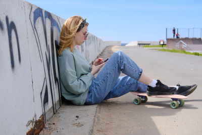 Side view of young woman sitting on street