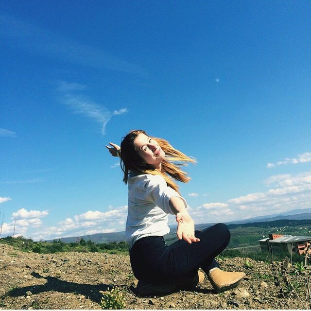 sky, lifestyles, leisure activity, young women, full length, casual clothing, young adult, long hair, standing, rear view, three quarter length, tranquility, field, grass, tranquil scene, arms outstretched, person, sunlight