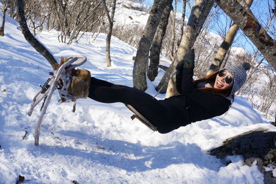 Full length of woman wearing snowshoe sitting on swing