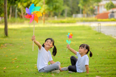 Cute little girl asia playing on the colorful toy windmill in her hands at the lawn.