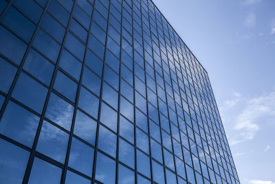 Low angle view of modern glass building against sky