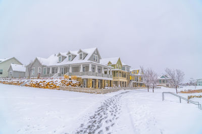 Snow covered houses by building against sky