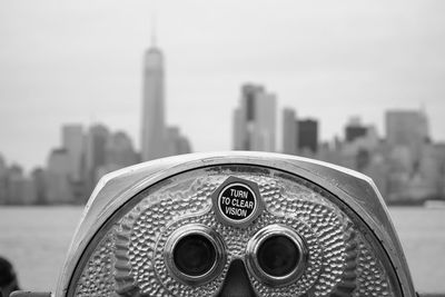 Close-up of coin-operated binoculars against cityscape