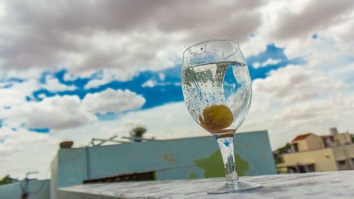 Close-up of beer glass against cloudy sky