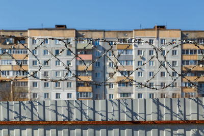 Residential multi-storey building behind a fence with barbed wire, restriction of freedom concept