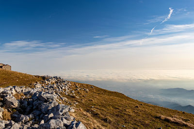 Rocks and grass on monte linzone with view of fog on the flat land