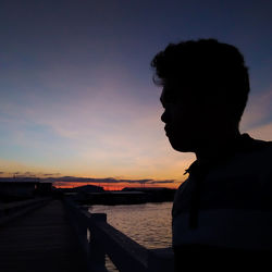 Silhouette woman standing by sea against sky during sunset