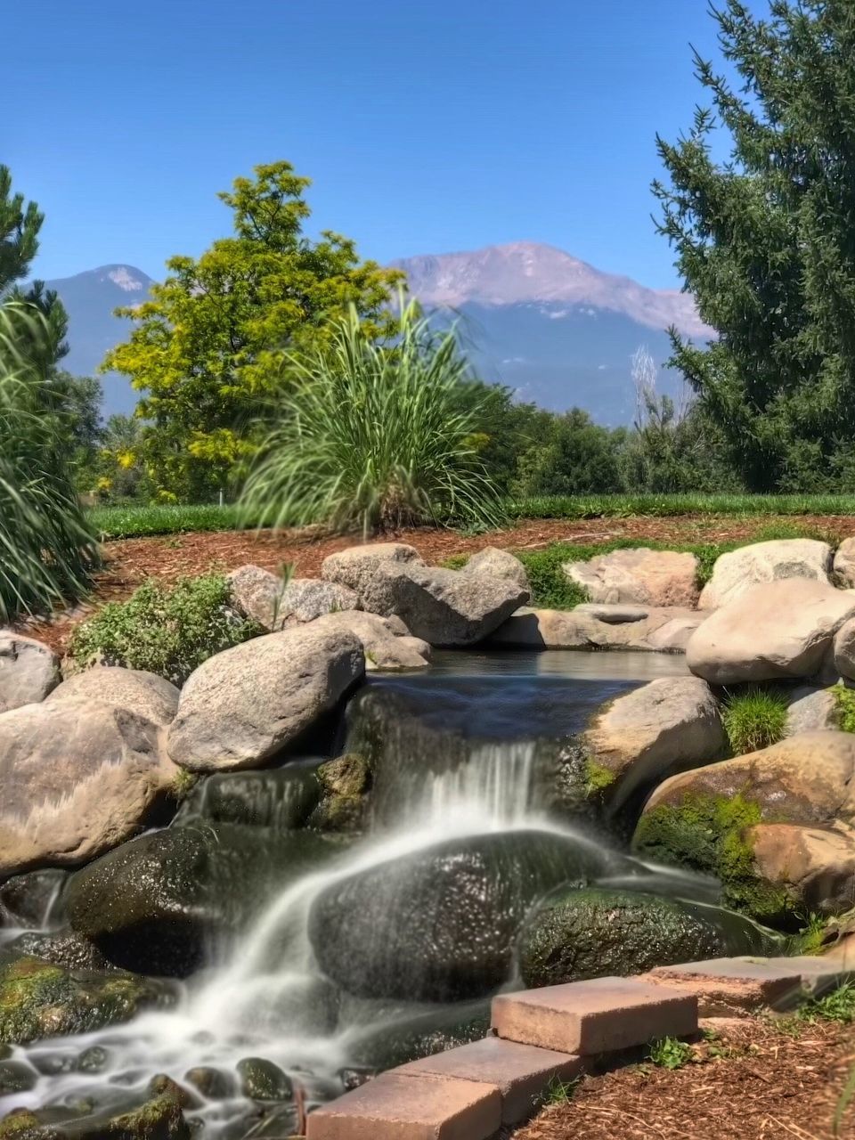 SCENIC VIEW OF WATERFALL BY ROCKS AGAINST SKY